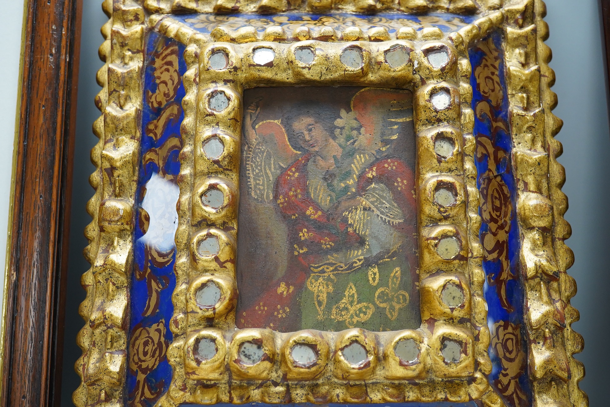 19th century, Retablo oil on board, Study of an angel or saint, 14 x 9cm, housed in an ornate gilt and reverse glass painted frame. Condition - fair